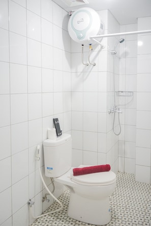 A bathroom with a toilet, a shower, and a toilet paper holder. - Elegant and Comfy 2BR Emerald Bintaro Apartment (South Tangerang)
