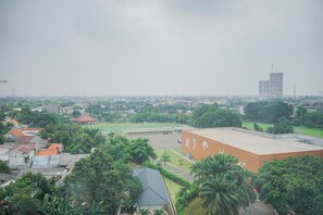 An aerial view of a cityscape with a large building with a flat roof and a distinctive white logo, surrounded by greenery and other buildings. - Elegant and Comfy 2BR Emerald Bintaro Apartment (South Tangerang)