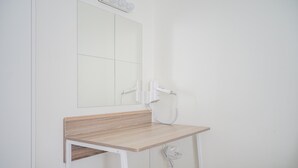 A bathroom with a wooden vanity, a mirror, and a white wall. - Minimalist Studio Bintaro Icon Apartment near British School (South Tangerang)