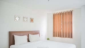 A neatly made bed with white linens, a brown headboard, and a white pillow. There are three wall-mounted decorative items above the bed. - Minimalist Studio Bintaro Icon Apartment near British School (South Tangerang)