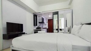 Une chambre d’hôtel moderne dotée d’un grand lit, d’une télévision à écran plat, d’une petite kitchenette et d’un dressing.