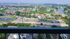 A cityscape with a river, buildings, and a roundabout. - Simply Look Studio Tamansari Mahogany Karawang Apartment (Karawang)