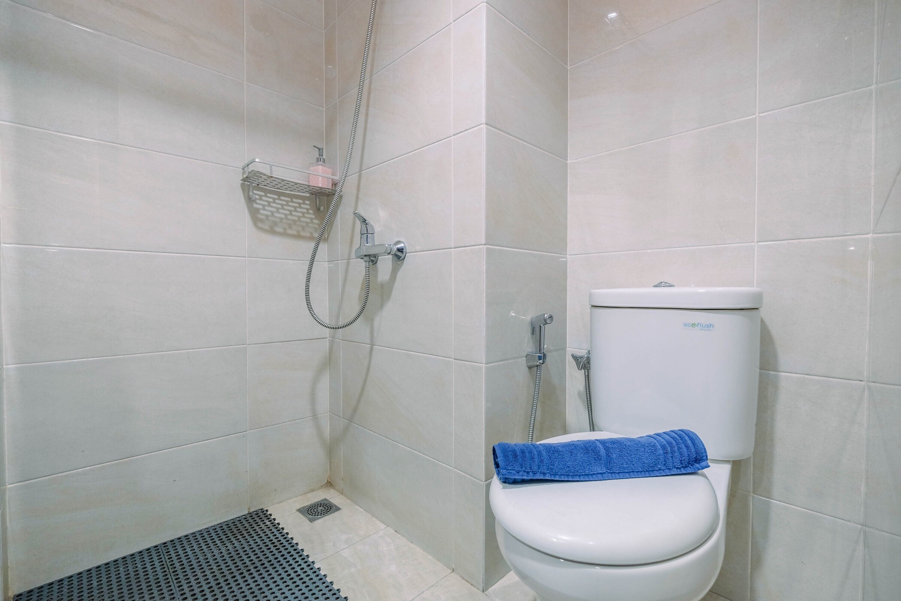 Un baño con inodoro, ducha y suelo de baldosas.