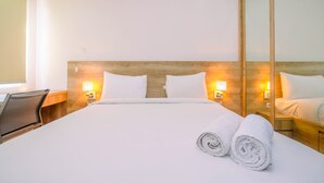 A hotel room with a large bed, two bedside lamps, a wooden headboard, a desk with a chair, and a mirror. - Minimalist Mustika Golf Residence Studio Apartment with City View (Cikarang)