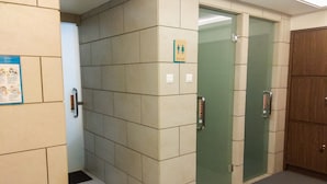 A restroom with a tiled wall, a glass door, and a wooden door. - Minimalist Mustika Golf Residence Studio Apartment with City View (Cikarang)