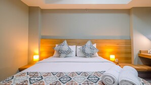 A hotel room with a large bed, two decorative pillows, a patterned bedspread, and two bedside lamps. - Comfortable 1BR Apartment at Mustika Golf Residence (Cikarang)