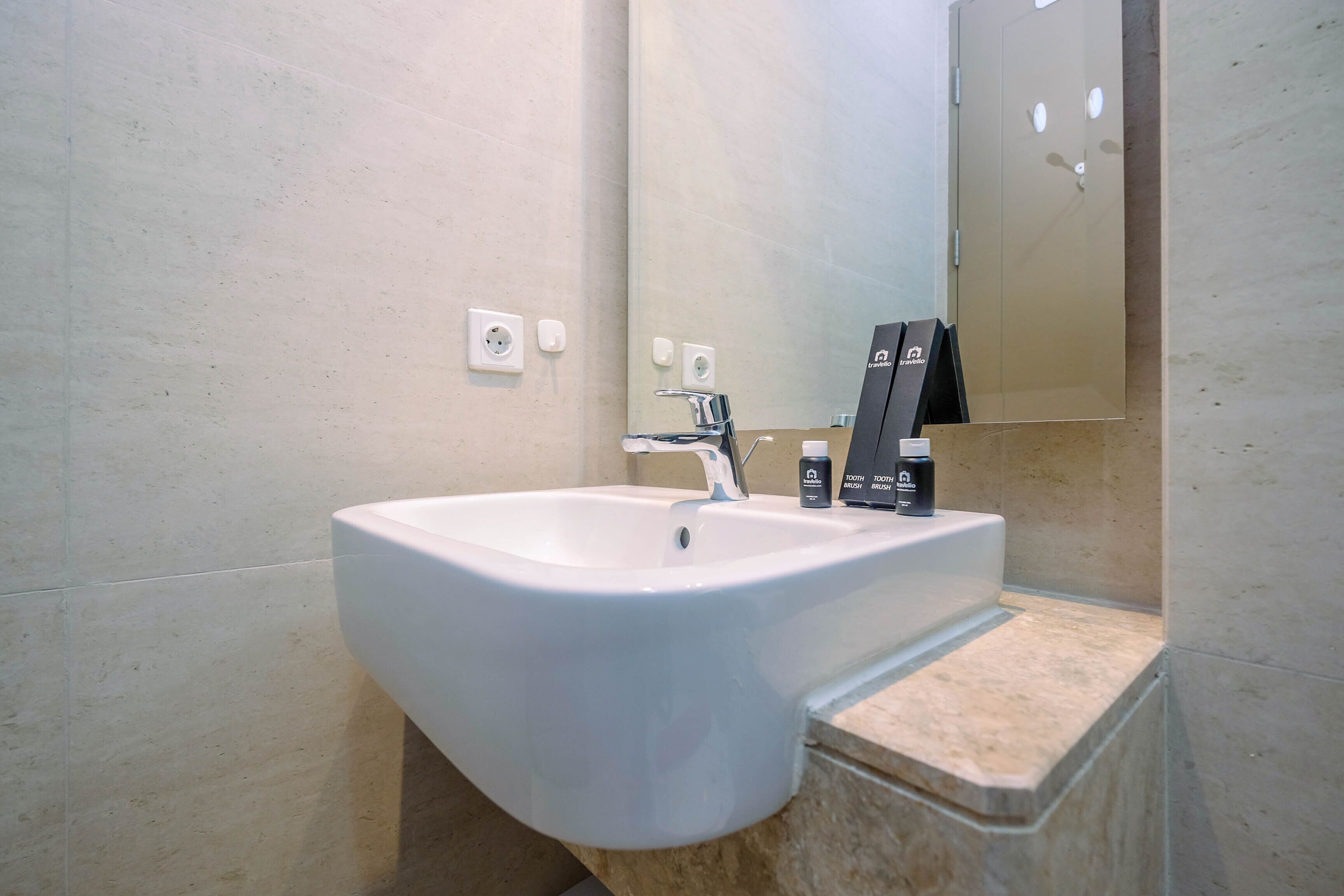 Een moderne badkamer met een witte wastafel, een spiegel en twee toiletartikelen op het aanrecht.