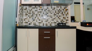 A compact kitchen with a checkered backsplash, a built-in microwave, and a coffee maker. - Compact and Cozy 2BR Kalibata City Apartment (Jakarta)