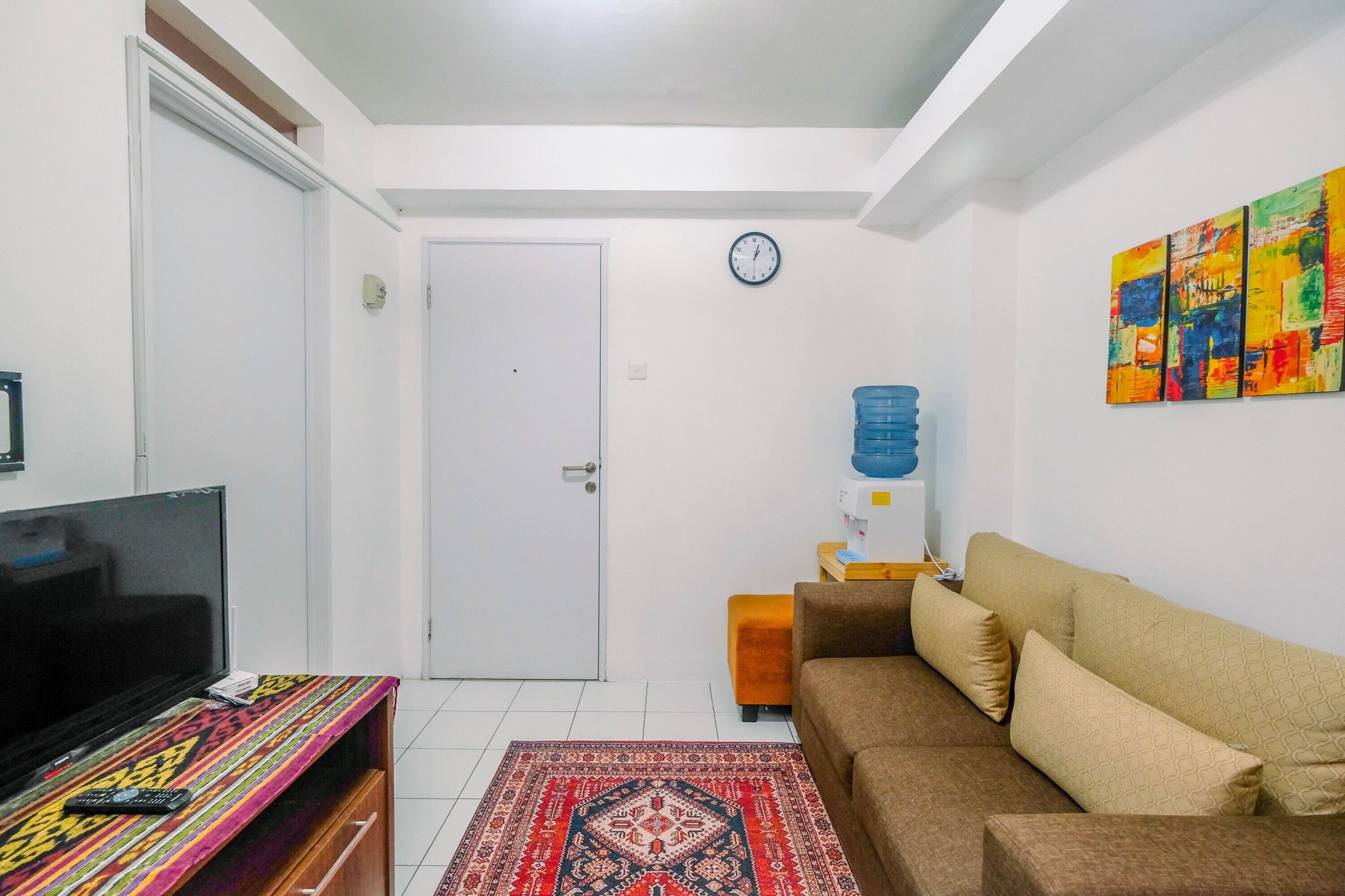 A living room with a television, sofa, and a patterned rug.