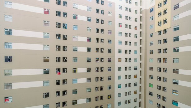 A high-rise building with multiple floors, each featuring numerous windows and balconies.