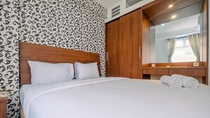 A neatly made bed with white linens, a wooden headboard, and a large mirror above the bed.
