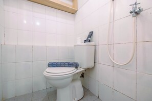 Et badeværelse med toilet, bruser og håndklædestige.