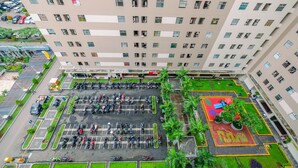 A multi-story building with a parking lot, a children's play area, and greenery.