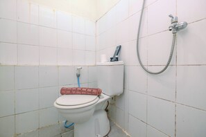 A small, basic bathroom with a toilet, a shower, and a visible pipe. - Minimalist 2BR Apartment at Kalibata City near Shopping Center (Jakarta)