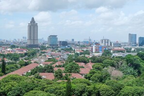 A cityscape with a prominent tall building, residential areas, and greenery. - New Furnished and Comfortable Studio Woodland Park Apartment (Jakarta)