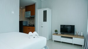 Ein modernes Hotelzimmer mit einem ordentlich bezogenen Bett, einem Fernseher auf einer Holzkonsolle und einem Kleiderschrank.