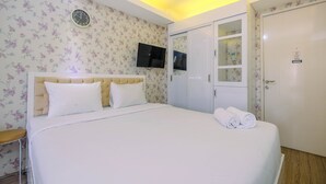 Un dormitorio ordenado con cama, televisor montado en la pared y armario.