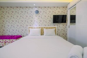 Une chambre à coucher avec un lit, une horloge murale, un téléviseur et une armoire.