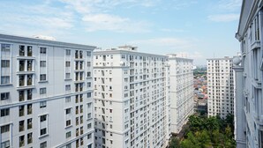 A high-rise residential building with multiple balconies, a clear sky, and a view of other buildings in the distance. - Comfort Stay Studio Room @ Green Palace Kalibata Apartment (Jakarta)