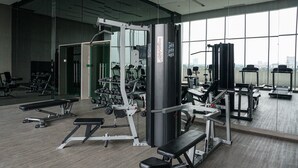Une salle de sport moderne dotée de divers équipements d’exercice, de grandes fenêtres et d’un aménagement propre et spacieux.
