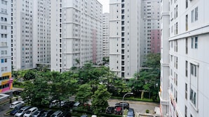 A high-rise residential building with multiple floors, a parking area in front, and surrounding greenery. - Wonderful and Cozy Studio at Green Palace Apartment (Jakarta)