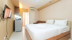 Una habitación de hotel con cama, escritorio, televisor y aire acondicionado.