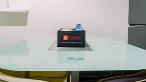Una mesa con cubierta de vidrio, con una caja negra etiquetada “travelio” y una botella de agua encima.
