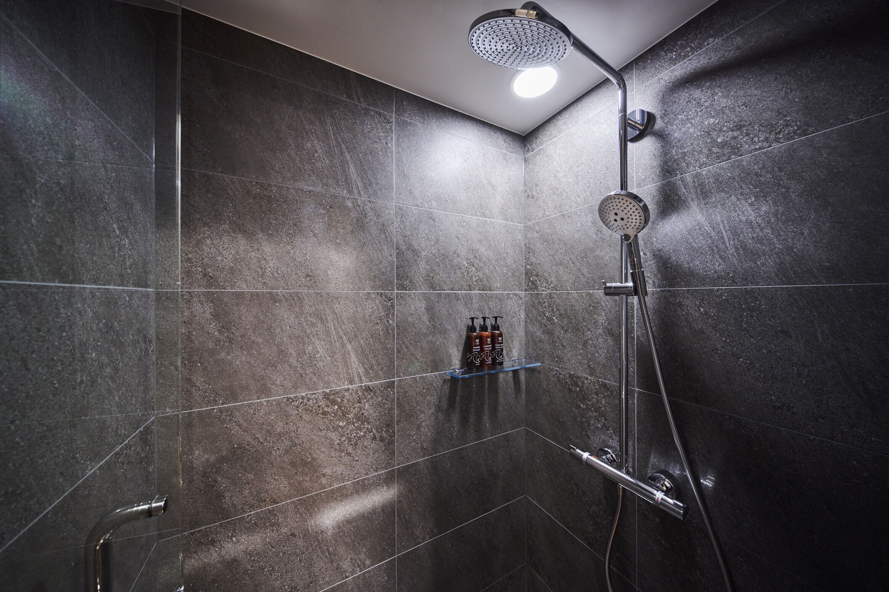 A modern shower with a handheld showerhead and a wall-mounted faucet.
