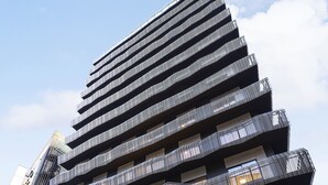 Un edificio moderno con un diseño escalonado distintivo, que presenta una entrada destacada con puertas de vidrio y un espacio exterior con asientos.