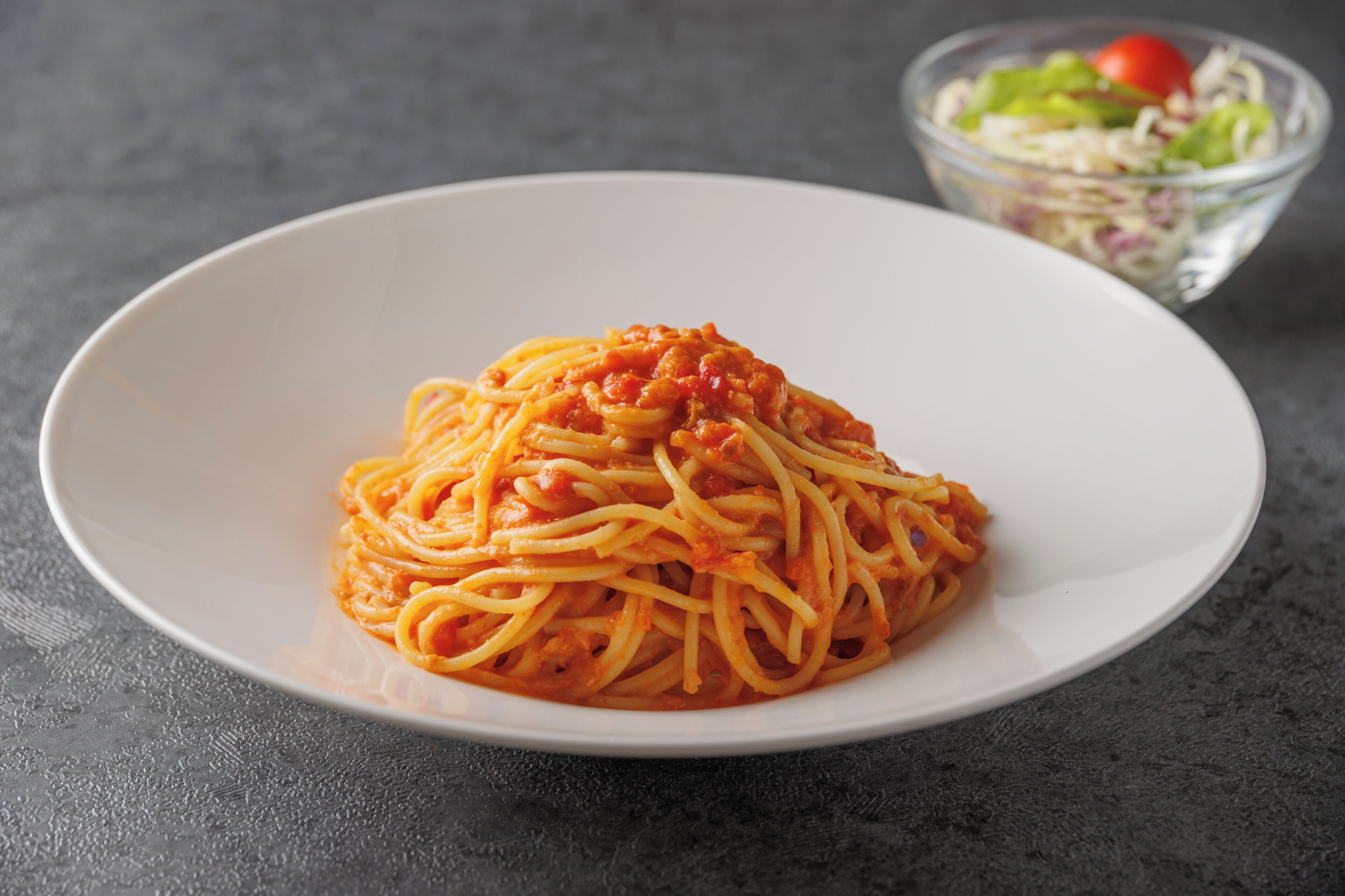 A plate of spaghetti with tomato sauce on a white plate.