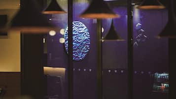 A modern interior with pendant lighting, a bar area, and a large illuminated wall.