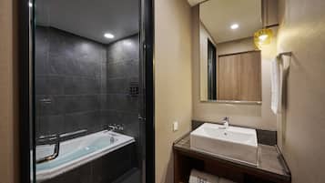 A modern bathroom with a glass-enclosed shower, a white sink, and a wooden vanity.