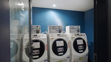 A laundry room with three stacked washing machines against a blue wall.