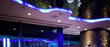 A modern indoor seating area with tables and chairs, large windows, and decorative wall art.