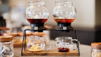 A coffee station with two glass carafes, a small pitcher, and a container with nuts and dried fruit.
