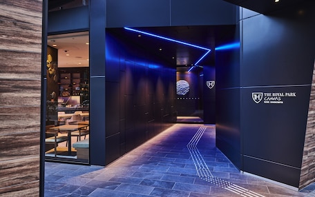 A modern interior with a dark color scheme, a logo on the wall, and a pathway leading to a seating area.