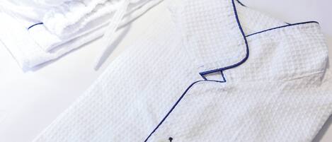 A neatly folded white shirt with a textured pattern and a blue trim along the collar and button placket.