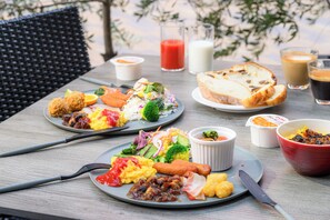 Une table dressée avec des assiettes remplies de nourriture, notamment des légumes, de la viande et du pain, ainsi que des boissons et des couverts.