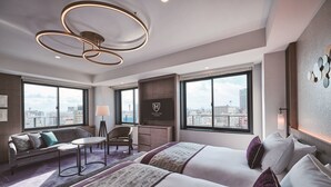 Una habitación de hotel moderna con dos camas, un sofá, un escritorio y un televisor.