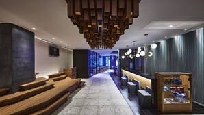 Un moderno vestíbulo de hotel con escalones de madera, un mostrador de recepción y una vitrina.