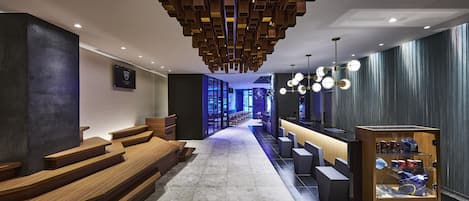 A modern hotel lobby with wooden steps, a reception desk, and a display case.