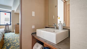 A hotel bathroom with a large white sink, a mirror, and a towel rack.