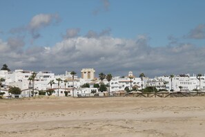 A coastal town with white buildings, palm trees, and a prominent tower.