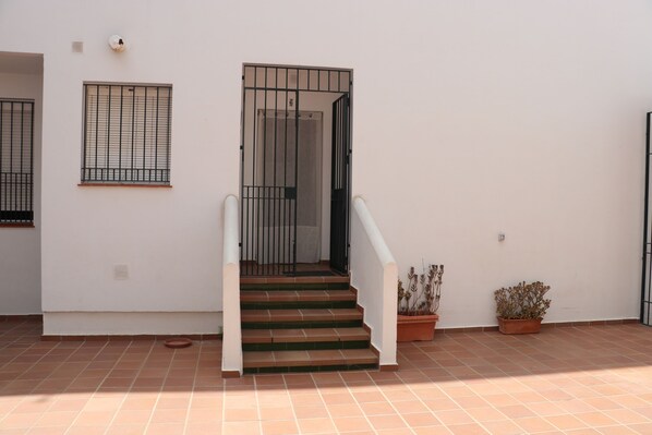 A staircase leading to a door with a metal gate, potted plants, and a tiled floor.