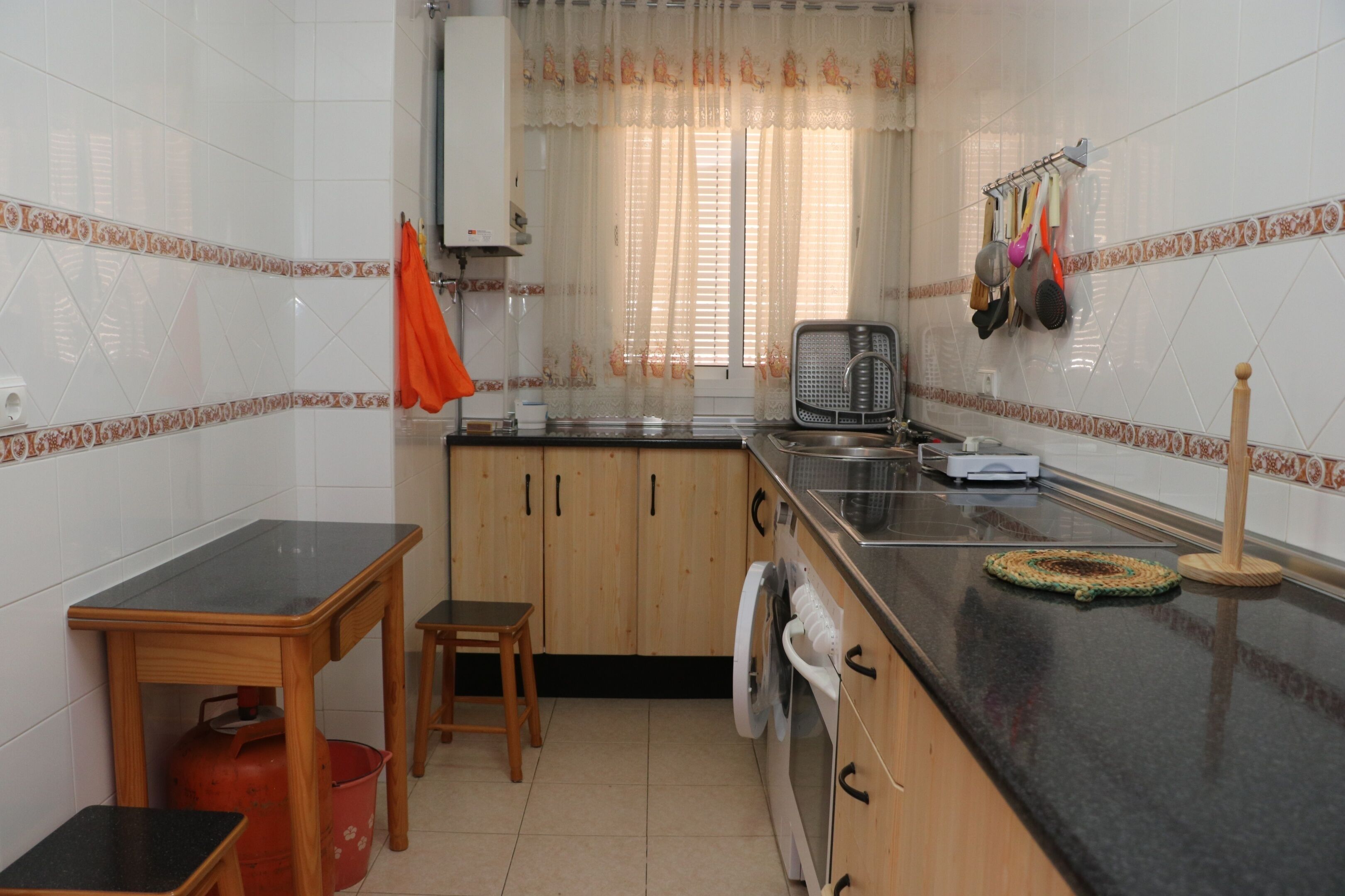 A kitchen with wooden cabinets, a washing machine, a sink, and a countertop.