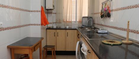 A kitchen with wooden cabinets, a washing machine, a sink, and a countertop.
