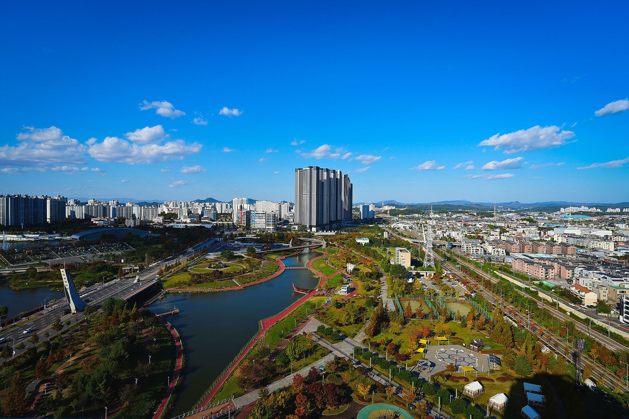A cityscape with a prominent high-rise building, a river, and a bridge.