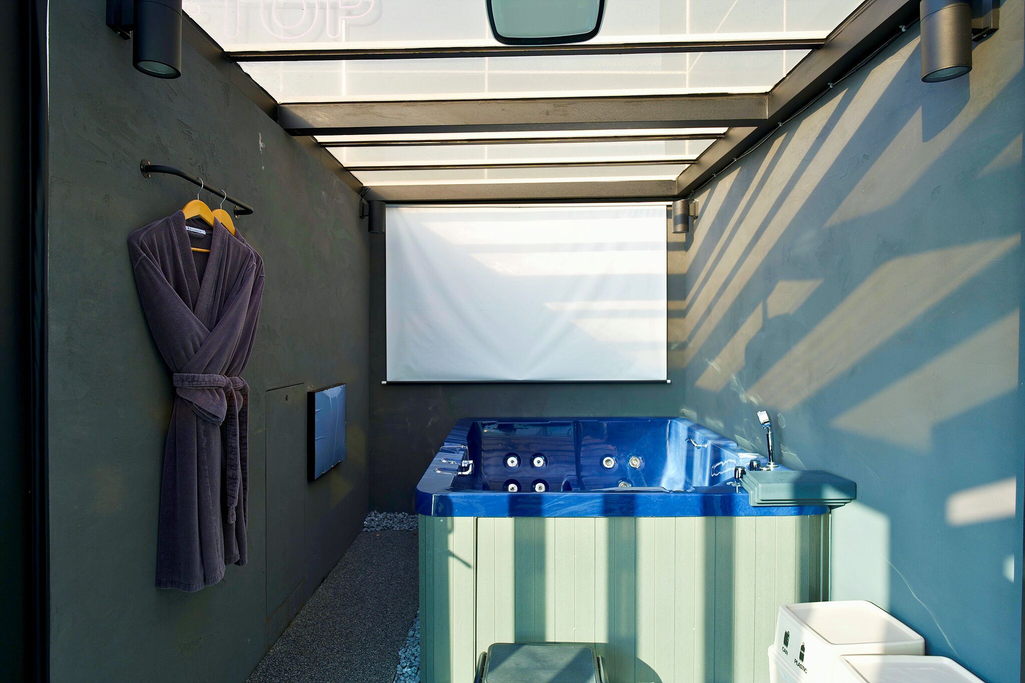 A spa area with a hot tub, a robe hanging on a rack, and a projector screen on the wall.