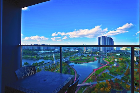 A balcony with a view of a cityscape, including a river, bridges, and high-rise buildings.