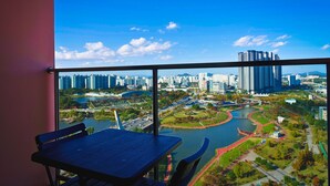 A balcony with a table and chairs, overlooking a cityscape with high-rise buildings and a river. - K-Hills The Terrace (Paju)